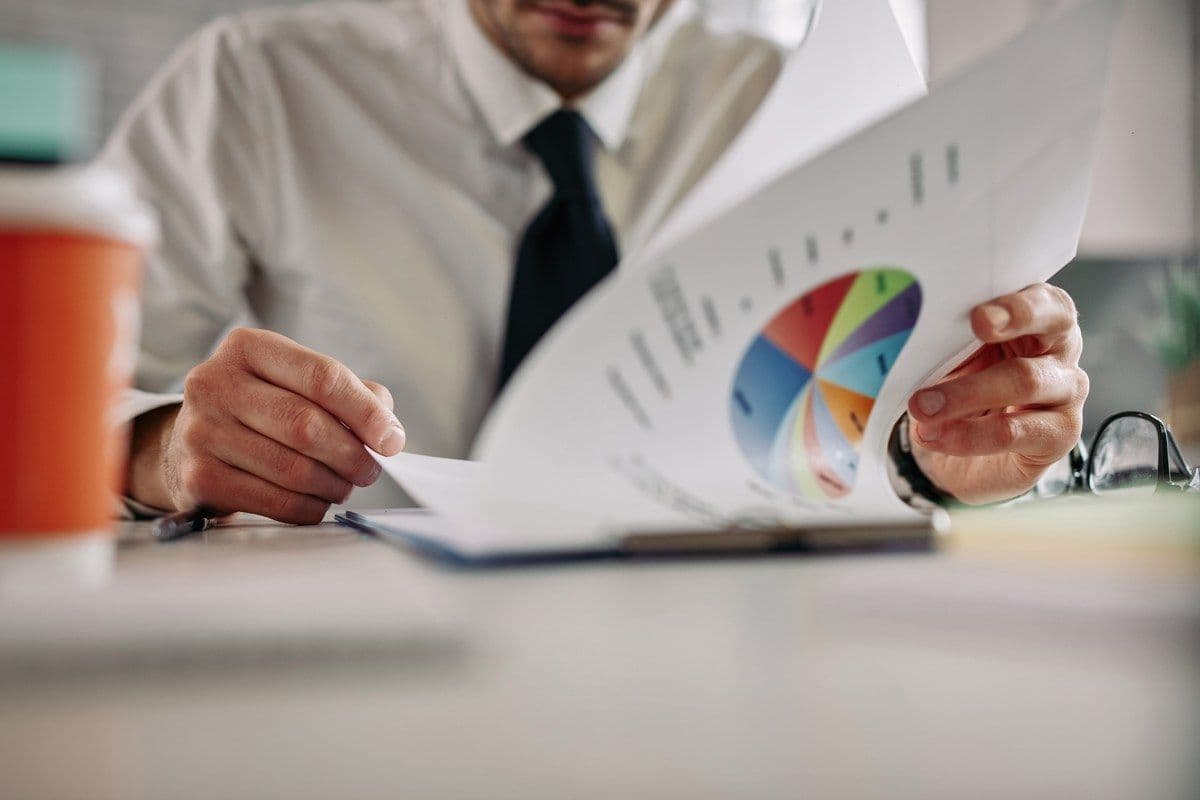 Executive reading a monthly management report with financial charts and KPI figures