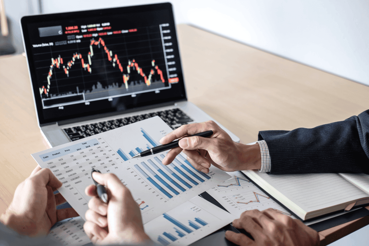 Two business professionals analyzing financial charts and data on paper and a laptop to ensure investment readiness.